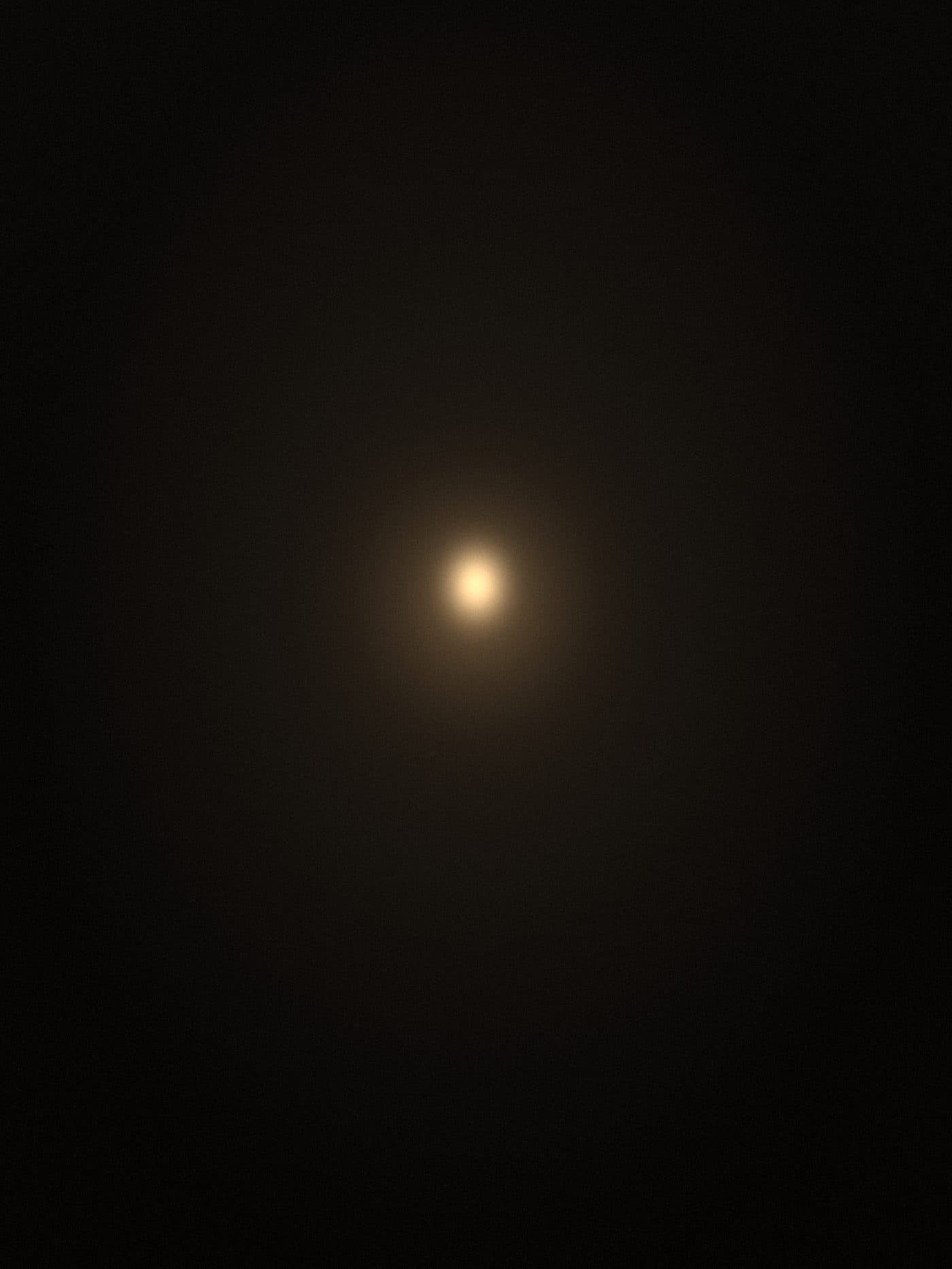 a single warm candle-like point of light in a dark room